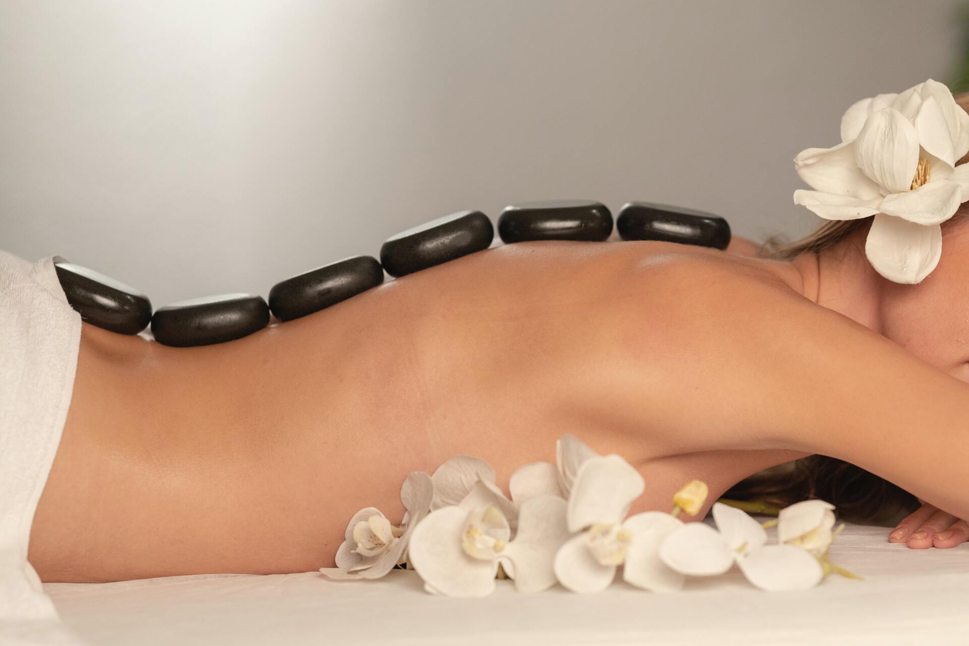 Hot stone massage with smooth basalt stones and orchids